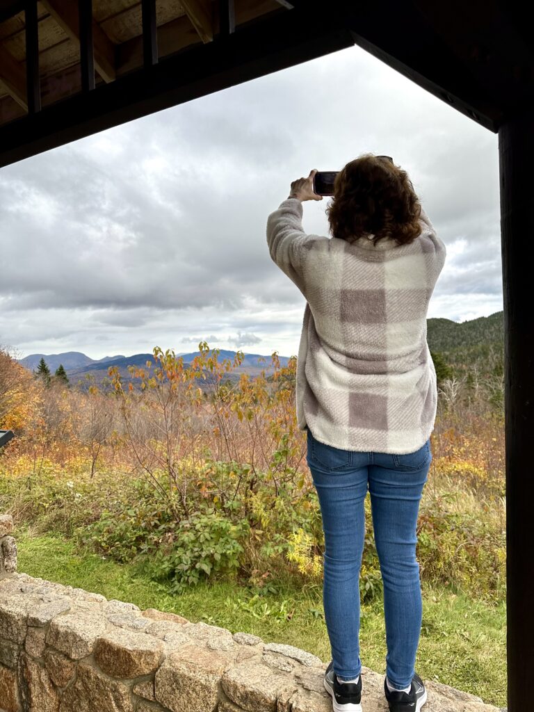 woman taking picture on phone of Wangan Overlook in New Hampshire