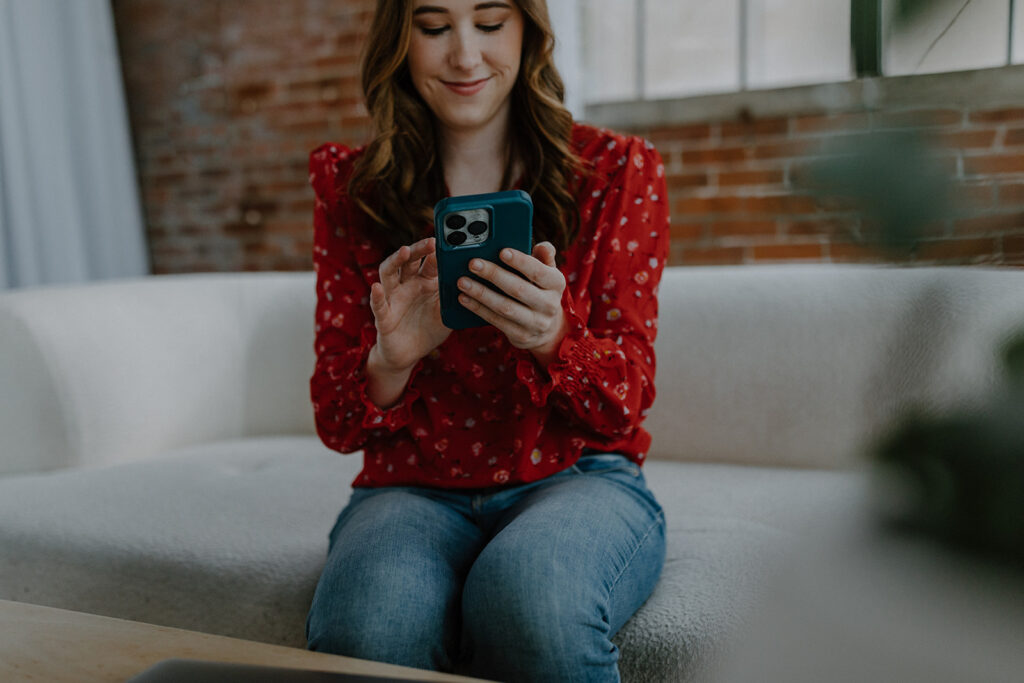 Woman holding phone and sitting on couch